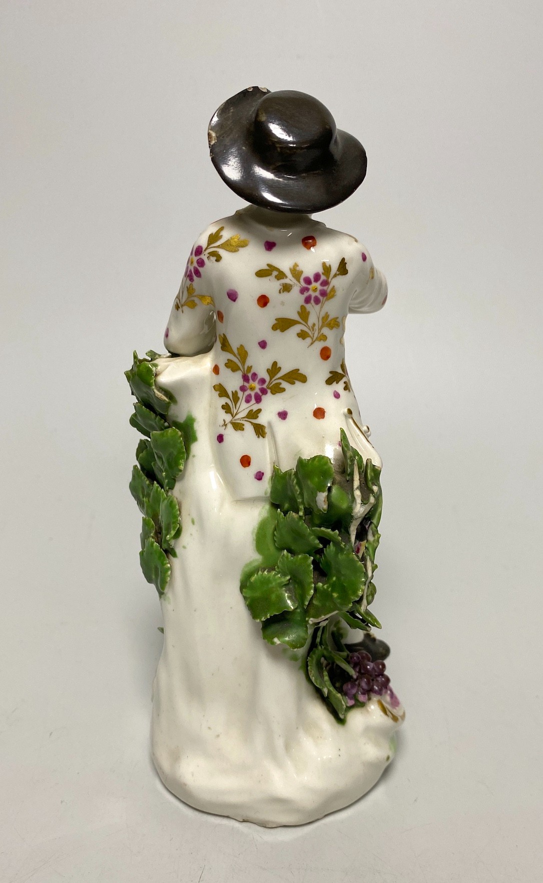 A Derby porcelain figure, emblematic of Autumn, modelled as a boy holding grapes and vine, 18th century, 18cm high